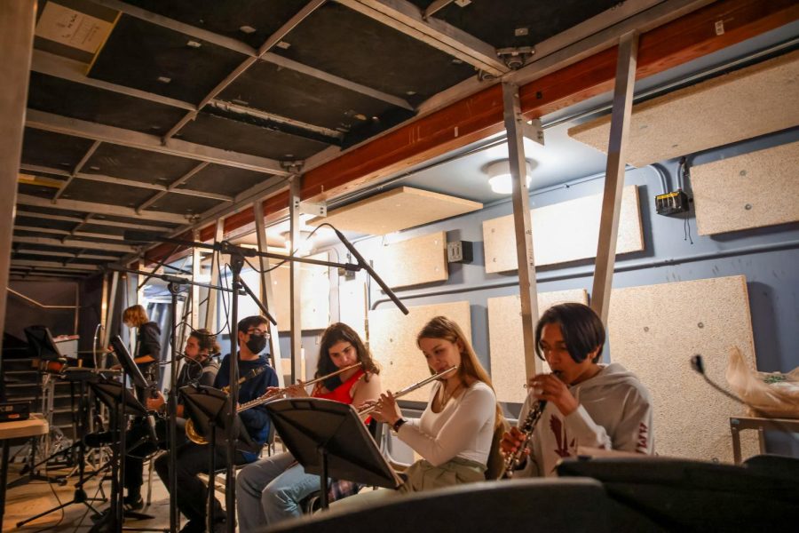 Tuning their instruments before a rehearsal, the 12 musicians playing during the show sit in the pit, guided by music director Marcus Swan and assistant music director and piano senior Sara Abdo.