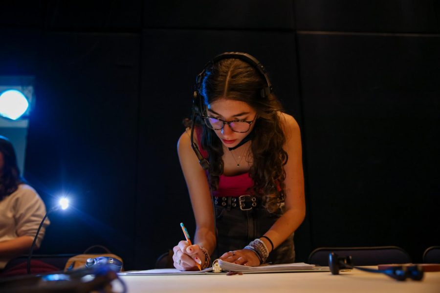 Preparing for the first runthrough in Meyer Hall, stage manager and theatre junior Devyn Humble adds notes to the script, outlining components to implement.