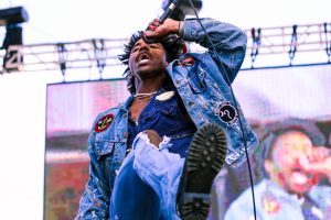 Alternative rapper De’Wayne, dressed head to toe in denim, kicks his leg out during his performance at the LaBovick Law Group Stage on Saturday, April 30. This was his first show of the year, and he made a point to interact with the audience whenever possible, responding to fan comments and remarking on the energy.
