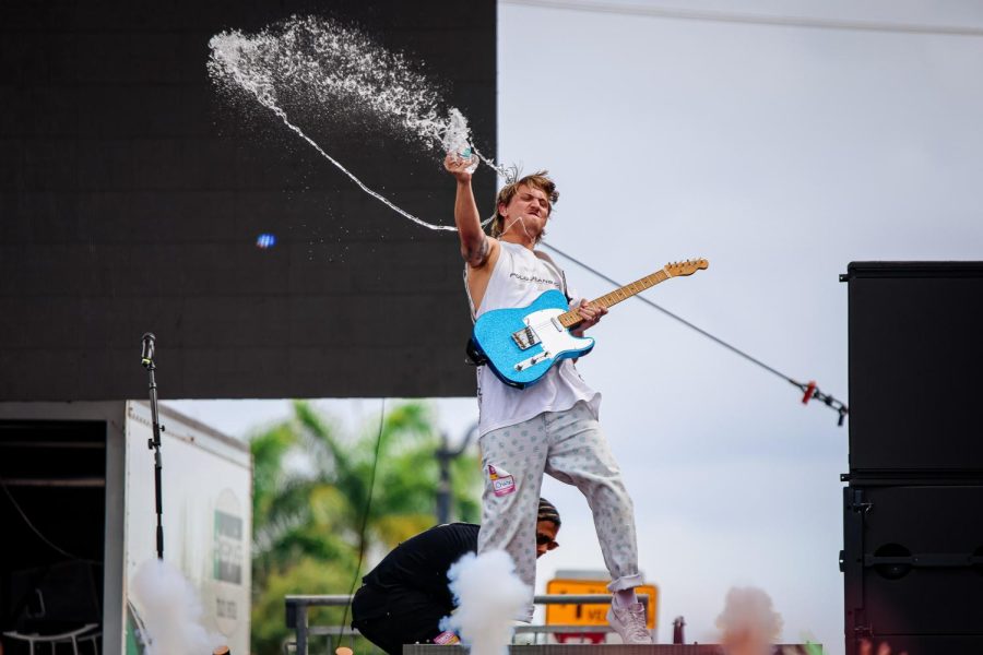 Guitarist and vocalist for Chase Atlantic, Christian Anthony sprays the crowd with water right before smoke blasts into the air in front of him.

