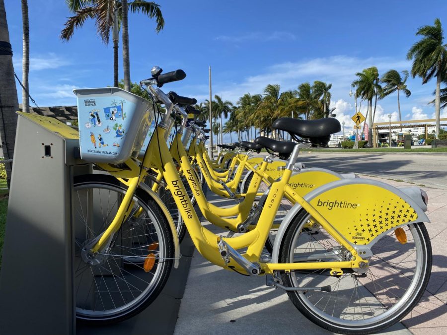 Parked at the corner of Flagler Drive and Clematis Street, a half dozen BrightBikes await riders. The bikes are located near the Brightline train stop and are easily accessible. People can rent them for a half hour at multiple stations throughout West Palm Beach, and riders do not need to return the bikes at the same stations they rented them from. 