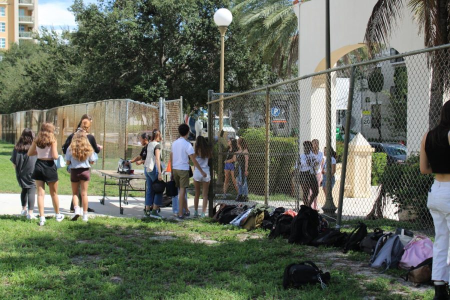 After placing their bags against the front gate of the school, seniors wait in line to get their IDs checked before they exit campus. During lunch, seniors are allowed to leave campus, known as senior privilege.