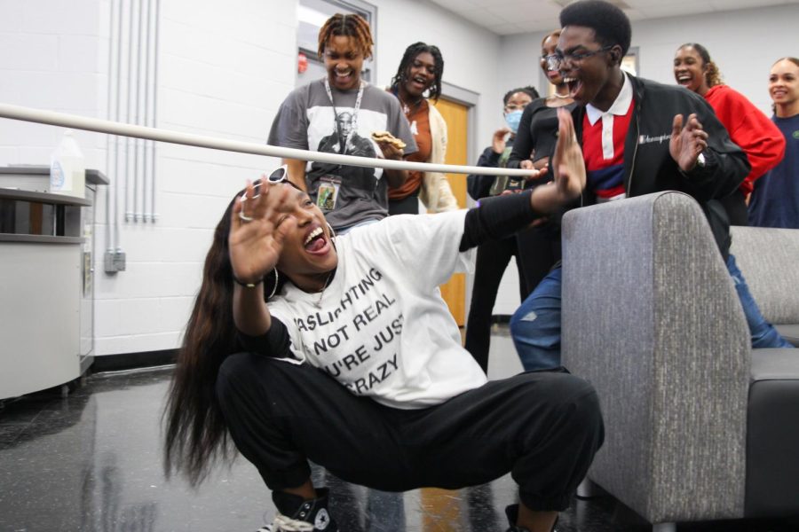 Crouching under the pole, visual sophomore Taniyah Aris participates in a game of Limbo in the media center during lunch on Feb. 8. Black Student Union (BSU) held a Game Day for the third day of BSU Spirit Week; it was meant to promote unity and allow students to play games that are iconic within the Black community. “It’s really enjoyable because I get to play games, listen to music, and talk to my friends that I don’t even have the time to talk to at school,” Aris said. 
