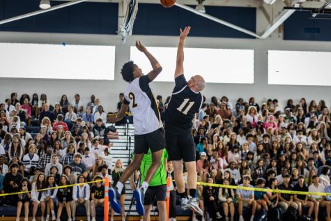 At the blow of the whistle, vocal junior Zidane Guerrier and athletic director Matthew Vaughan jump into the air, reaching for the ball during the teacher versus student basketball game. 