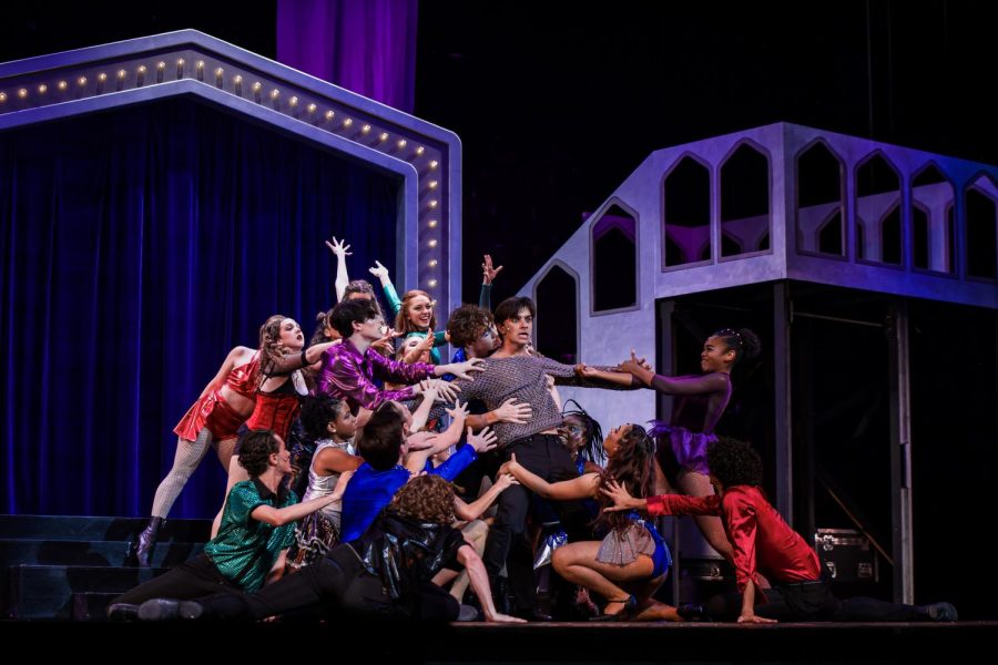 Decked in colorful costumes, the “Pippin” ensemble lunges forward to grab Pippin (played by theatre senior Mason Materdomini), representing his victory celebration during “With You.”
