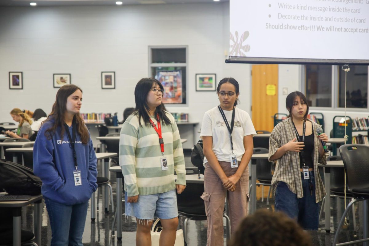 Standing among other NAHS officers, vocal senior and co-vice president Hope Luo (far right) explains participation hour opportunities to members.  NAHS not only has expanded their participation hour opportunities to Cards for Care, but to other organizations around campus, including Seeds Literary and Arts Magazine.
