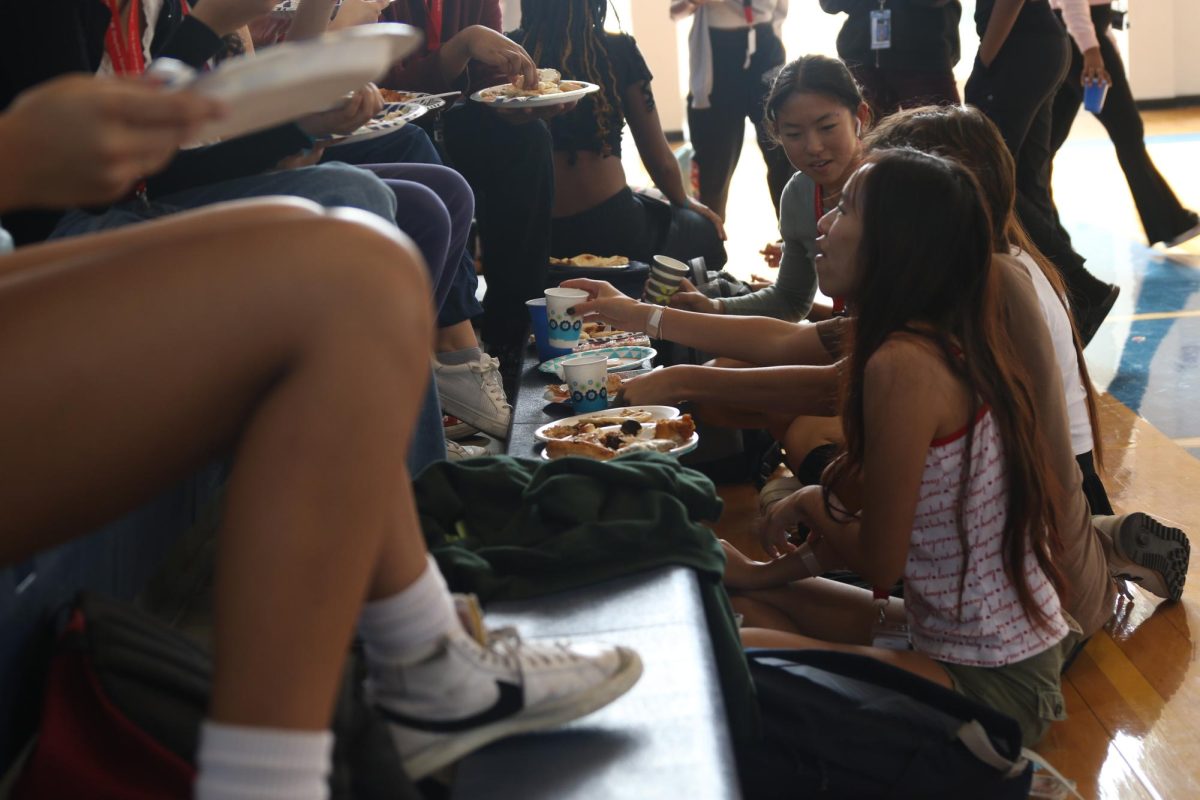 Visual junior Thi Tang eats on the bleachers with others at the Multicultural Potluck, held Nov. 10. 