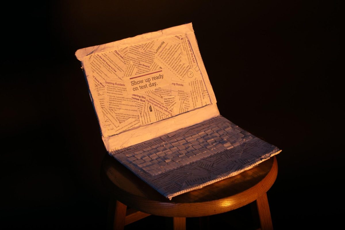 A paper mache computer crafted out of SAT practice test packets bears the words Show up ready on test day, in the center of its screen.
