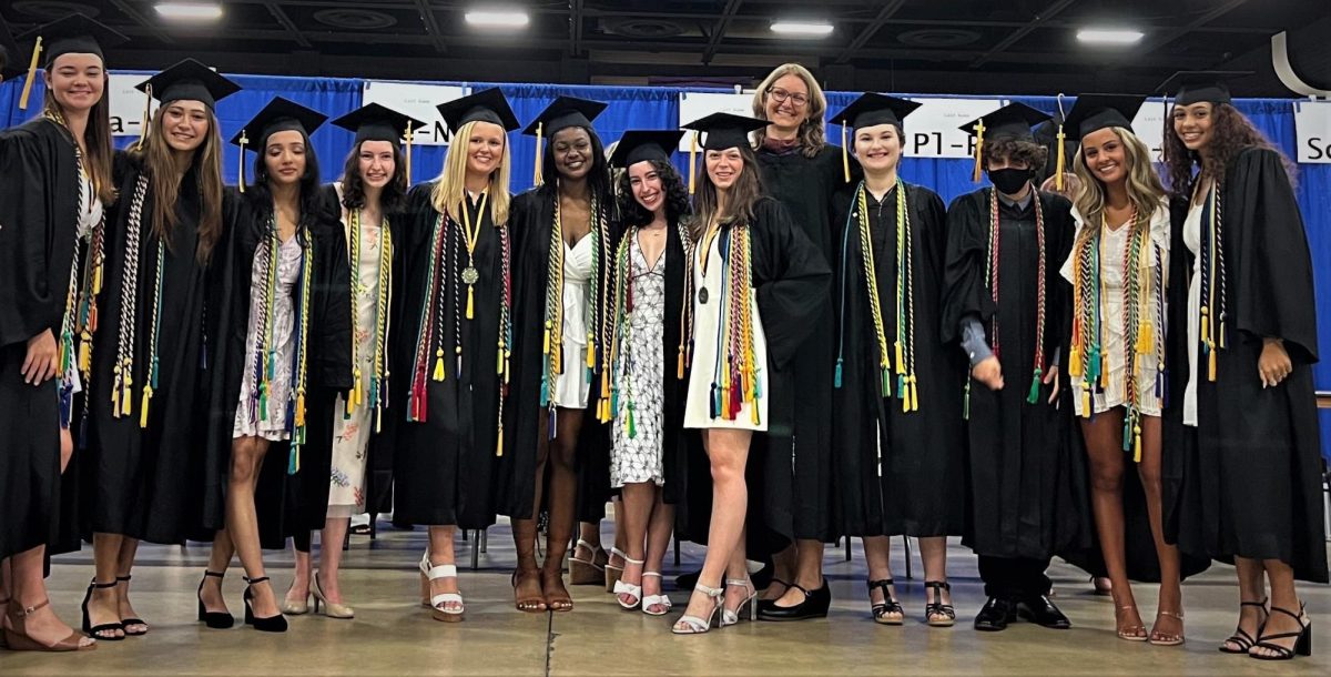 Seniors from the Class of 2022 pose with The Muses adviser, Carly Gates, at graduation.