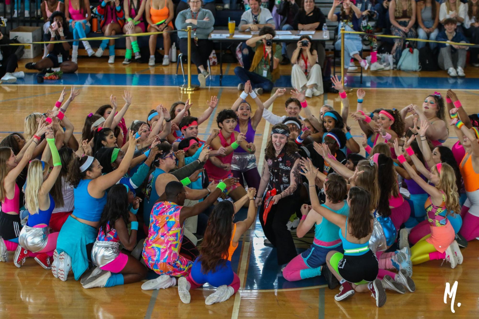 Pretending to play an inflatable guitar, digital media senior Coral Johnston performs in the Generations Dance with other seniors. The class of 2024 dressed up as part of the ’80s generation.