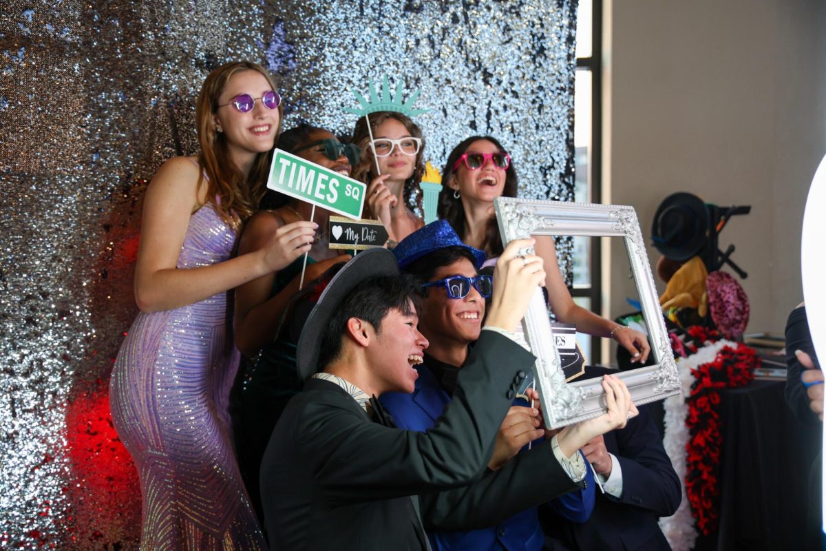 Vocal juniors Austin Yu, Peter Hennessey-Correa, and their peers pose for a picture with New York-themed props in a photo booth at this year’s prom.