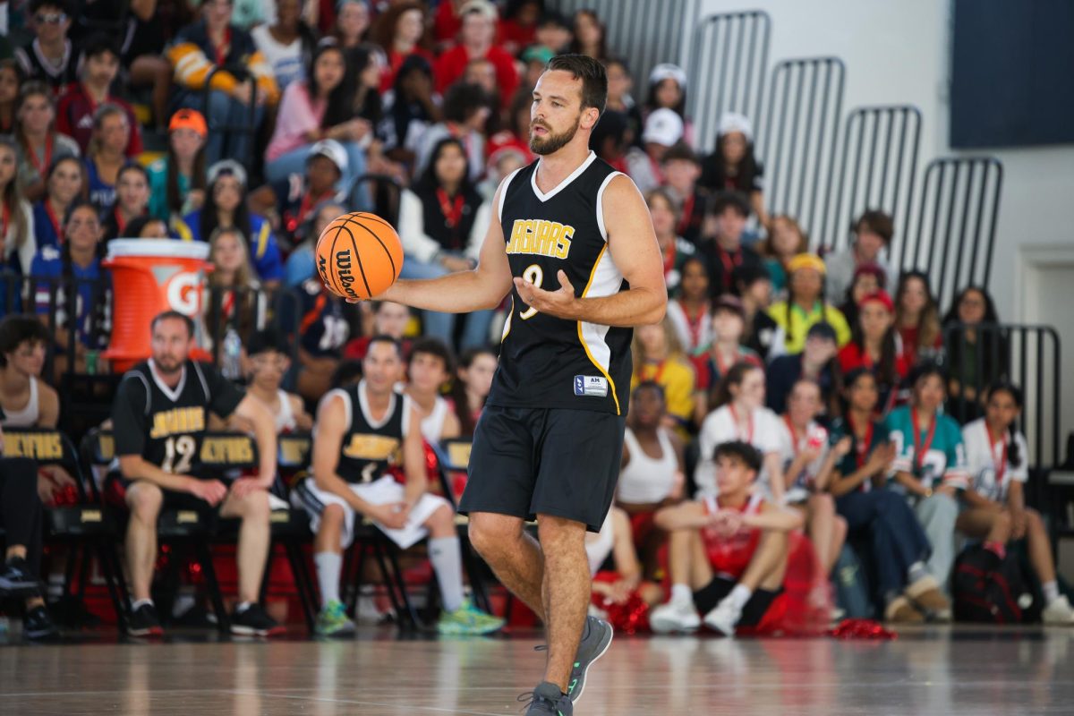Running across the court, assistant principal Drew Dawson dribbles a basketball in his hand. 
