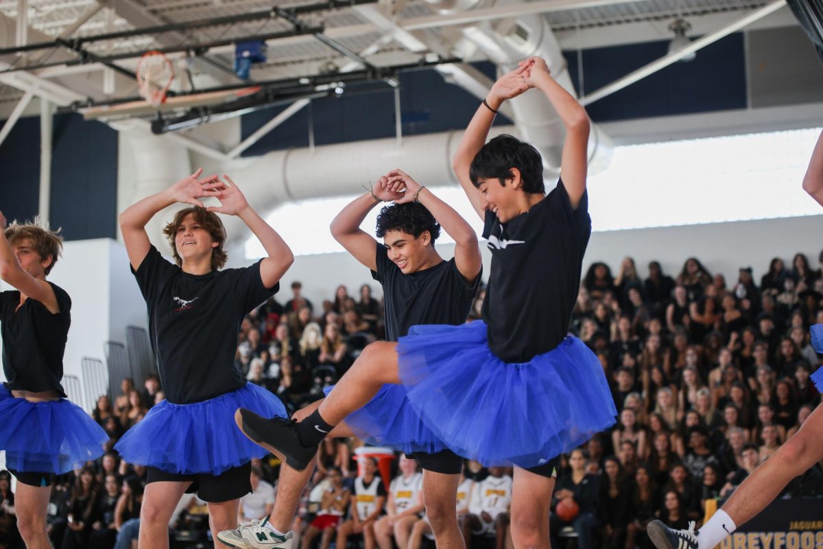 Dancing with his arms up high, strings freshman Angus Murphy performs in his class’ Powderpuff routine during halftime of the Students vs. Teacher basketball game. “Powderpuff was so much fun, and I am thankful for the few students who stepped up to the occasion,” Murphy said. “I’m looking forward to next year’s group already.”

