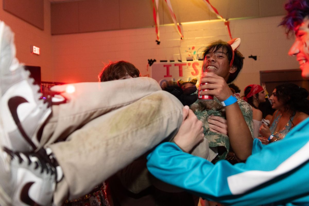 Hoisted up in the air by his friends, band sophomore Janssen Domingo drinks a Coke on the dance floor. 
