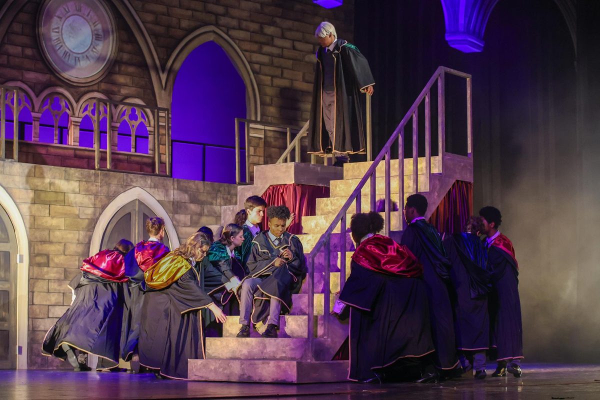 Staring down the staircase, theatre senior Darien Batistia (Scorpius Malfoy) avoids eye contact with theatre senior Kevontay Oliver (Albus Potter). The staircases were made by students from the technical theatre and visual arts departments, and were disassembled after the final showing of the play. The extra parts were donated to Bak Middle School of the Arts’ theatre program.