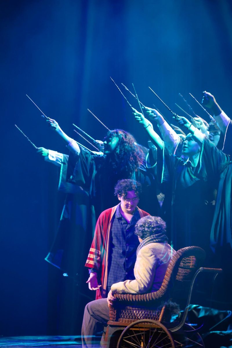 In a double exposure photo, actors representing Hogwarts students wave their wands in the air, while theatre senior Connor Hullender (Harry Potter) speaks with theatre junior Philip Xenick (Amos Diggory) about the past trauma they experienced when the character Cedric Diggory (played by theatre senior Andrew Hopta) died.