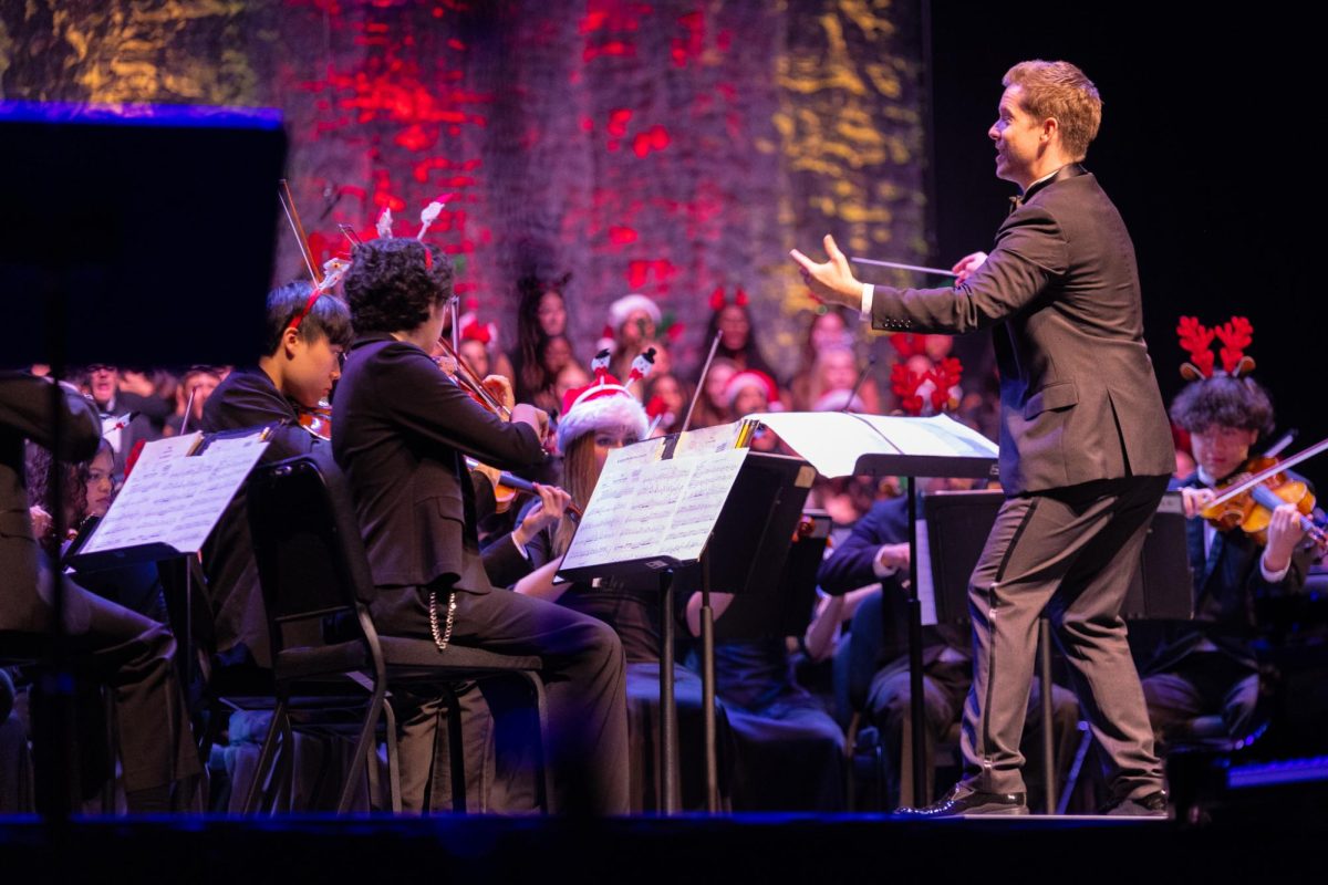 Conducting the orchestra, strings teacher Jeffery Adkins guides an orchestra to perform “Spirit of the Season.” 