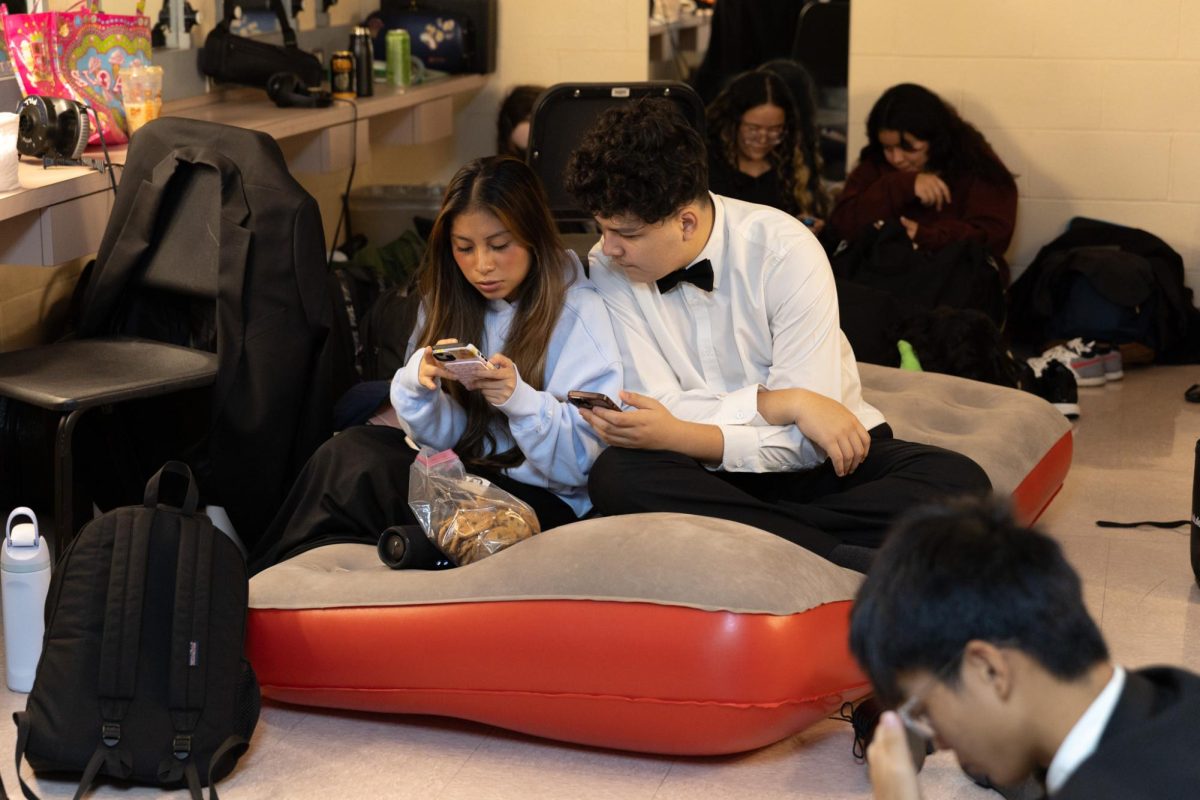 Sitting together on an inflatable mattress, band sophomores Adriana Lopez-Tzun and Anthony Vera wait in a backstage room to be called for their next performance. Students who participated in the Prism concert stayed in the Kravis center Dec. 2 from 8:30 a.m. to 1:00 p.m. for the daytime rehearsal. 