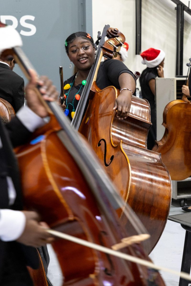 Carrying her bass through a crowd of students outside of stage right, band senior Tianna Grannum transports her instrument after performing in the pre-show. “It was definitely a bit jarring seeing the audience filled,” Grannum said. “But when I looked at my stand partner and my bass section, (I had) more of an excitement feeling than anything.”