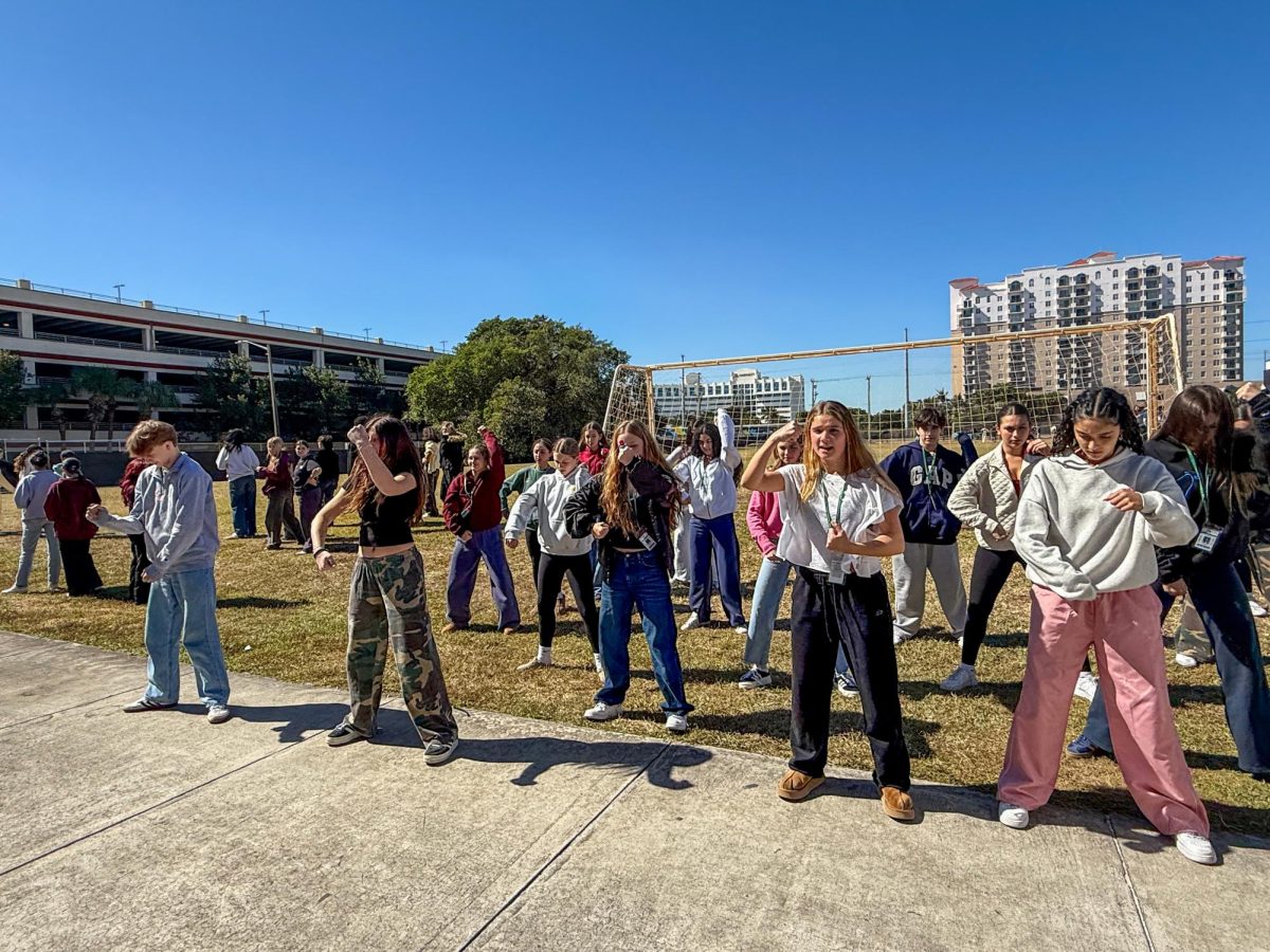 Putting their hands in the air, sophomore students practice one of their Spirit Week dances near the soccer field Feb. 6. Student performers from each grade level started to prepare for their Spirit Week dances in January, rehearsing one to four times a week during lunches.