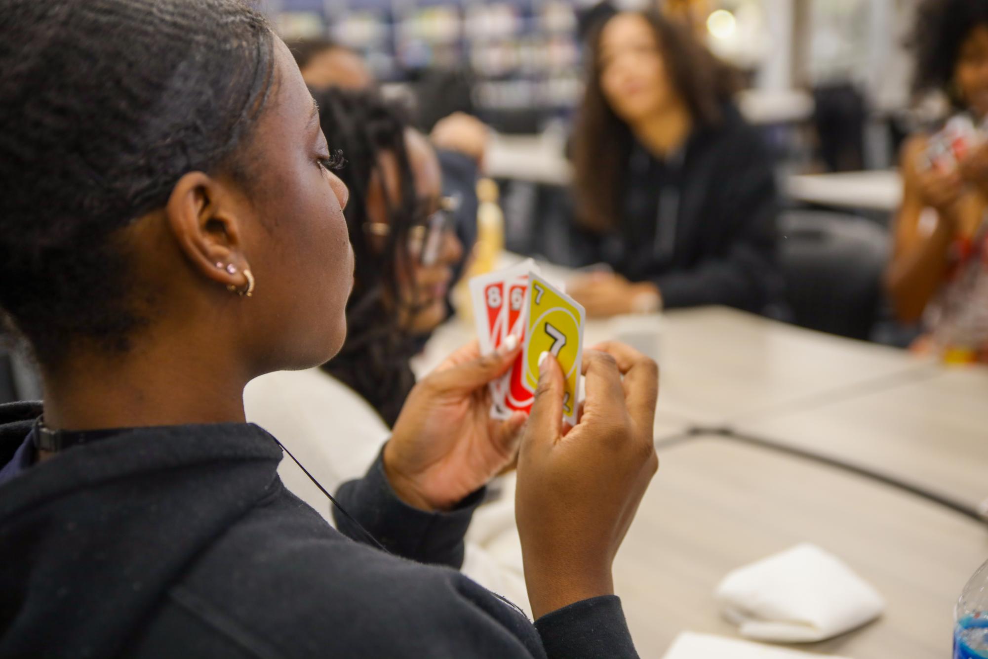 Holding her cards away from other players, vocal senior Edeisha Sainvil plays a game of Uno. BSU’s Game Night event took place in the media center Feb. 24.

