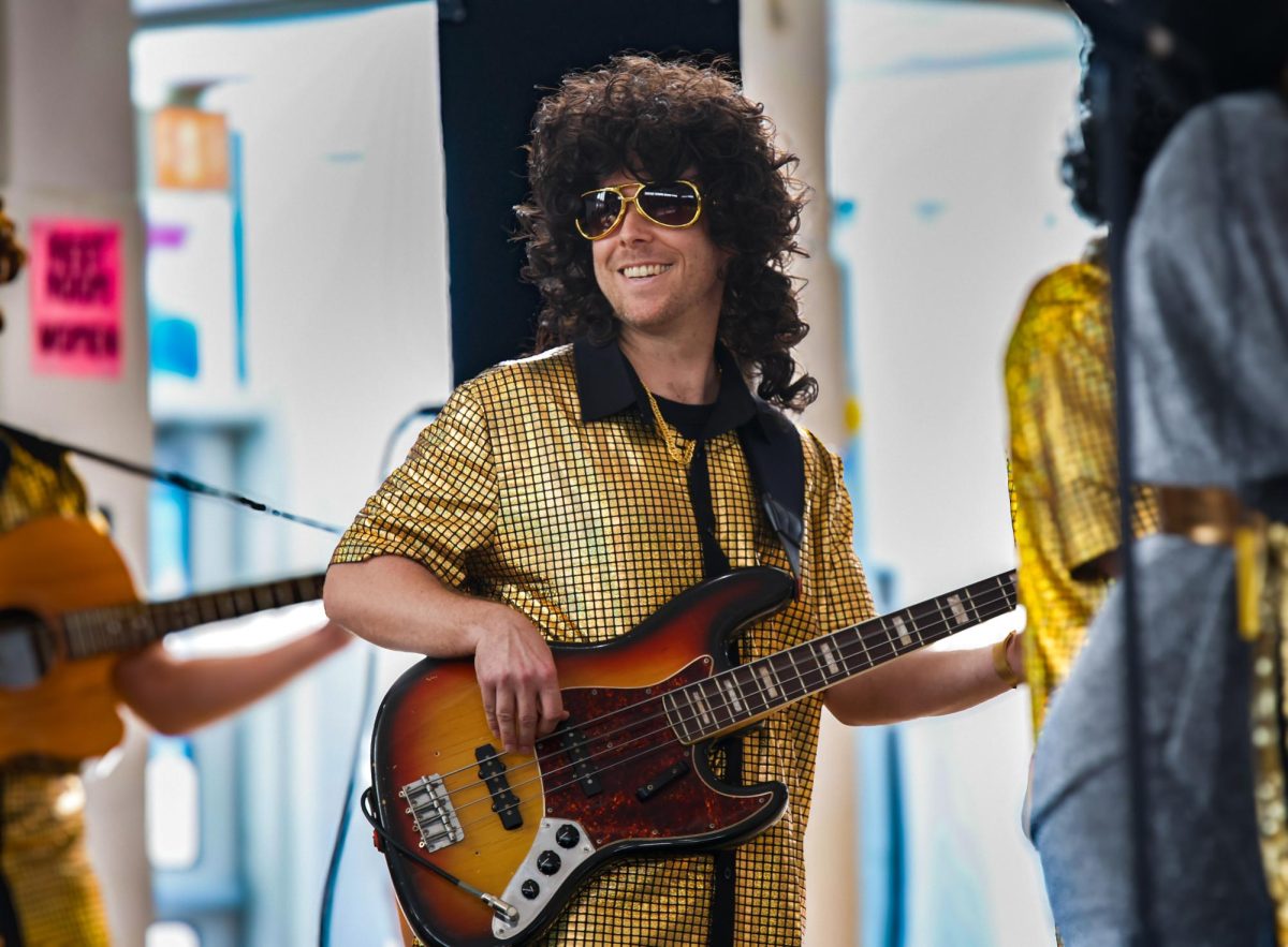 Playing the bass, orchestra director Jeffry Adkins, along with faculty and staff, surprises the student body with a performance of "I Will Survive" by Gloria Gaynor from their band, “Finney and the Goldstones.” 