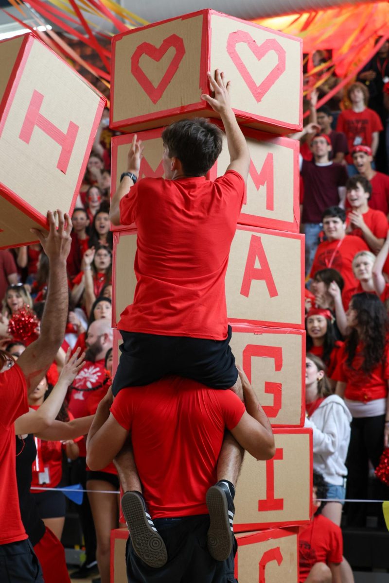 Placing the last two remaining blocks in the Magic Block Stacking Game, theater junior Zachary Fischetti rides vocal junior Eric Bolanos’ shoulders; the juniors finished in 2nd place. The teams’ goal was to stack blocks vertically to spell out, “I ♡ MAGIC!” Magic Block Stacking was a new addition to the Pep Rally this year. 