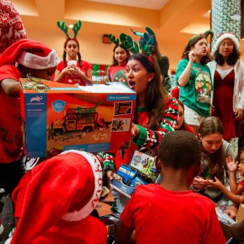 Surrounded by children and volunteers decked in festive attire, vocal junior Annika Rhoads helps an elementary school student unwrap his gift at the Dec. 8 Jefferson Jubilee. Hosted by ARTS Club each year, the event is an opportunity to share the holiday cheer with over 50 underprivileged kids from four elementary schools throughout Palm Beach County with surprise performances from student volunteers dressed as Elsa and Anna, Santa and Mrs. Clause, and even the Grinch.