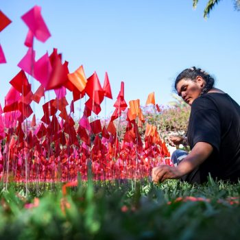 Visual sophomore Brisny Munguia places a utility flag in the ground as part of an installation that incorporated 9,000 red, orange, and pink flags in the shape of a compass. Designed by artist Patricia van Dalen, “The Compass” is on display at The Society of the Four Arts after visual students volunteered to assist with the Dec. 10 installation.