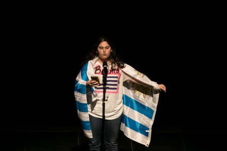 Holding the flag of Uruguay, communications freshman Bianca Angelino recites her poem about how she feels her heritage deserves more respect.