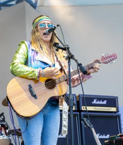 Strumming her guitar, lead singer of the Fox Maple Band, Fox Maple, sings on the Ideal Nutrition Stage.