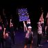Raising a sign in the air reading “Class of 2028,” theatre freshman Tristan Dominguez performs in a group piece titled, “Seize the Day” from “Newsies” by Alan Menken.