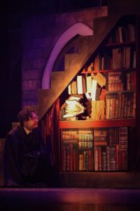 Widening his eyes, theatre senior Connor Hullender (Harry Potter) gazes at the book speaking from within a bookshelf.