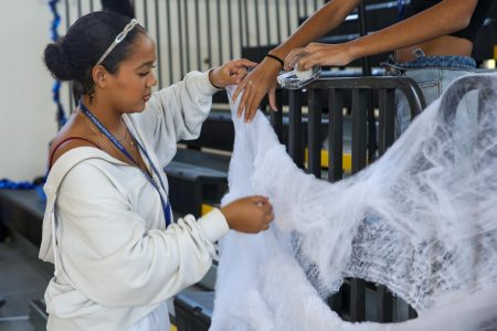 Placing cobweb decorations, communications freshman Peyton Davis accessorizes the rails of the bleachers for the upcoming Fall Festival, an annual event held on Halloween in the gym. Students can watch and participate in games to win Pep Rally points for their grade level.