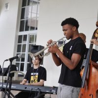 Playing his trumpet, fourth year member of the student jazz band The Brothers Five and band senior Matthew Harper performs a riff on the saxophone during the group’s first “Jazz by the Shack” performance outside the cafeteria this school year.