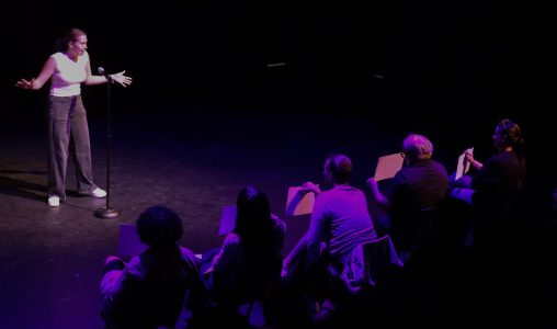 Reading the scores of a previous presenter from lowest to highest, Slam Poetry Vice President and communications junior Maya Bourak averages the scores in front of the audience.