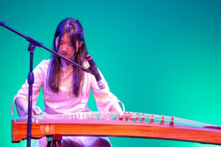 Strumming the strings of the guzheng, piano sophomore Avery Li accompanies singers during Asian Cultural Society's (ACS) Chinese heritage performance during the multicultural showcase. The guzheng is a traditional Chinese instrument which typically has 21 strings and is played by hand.