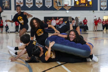 Screaming at her teammates, vocal senior Lena Powery grabs and rides a mattress in Mattress Rolling, which was a new game addition in the Pep Rally this year. The goal of participants was to lie on the floor and roll a teammate on top of a mattress to the other side of the gymnasium.