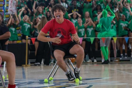 Sticking his tongue out to the junior class, vocal junior Leonard Ward celebrates after finding a seat during a round of musical chairs.