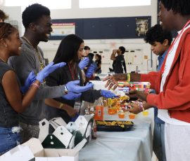 Digital senior Joseph Floreal and theatre senior Aissa Duclervil converse with band junior Megas Verdieu while handing out food at the Black Student Union (BSU) table set-up.